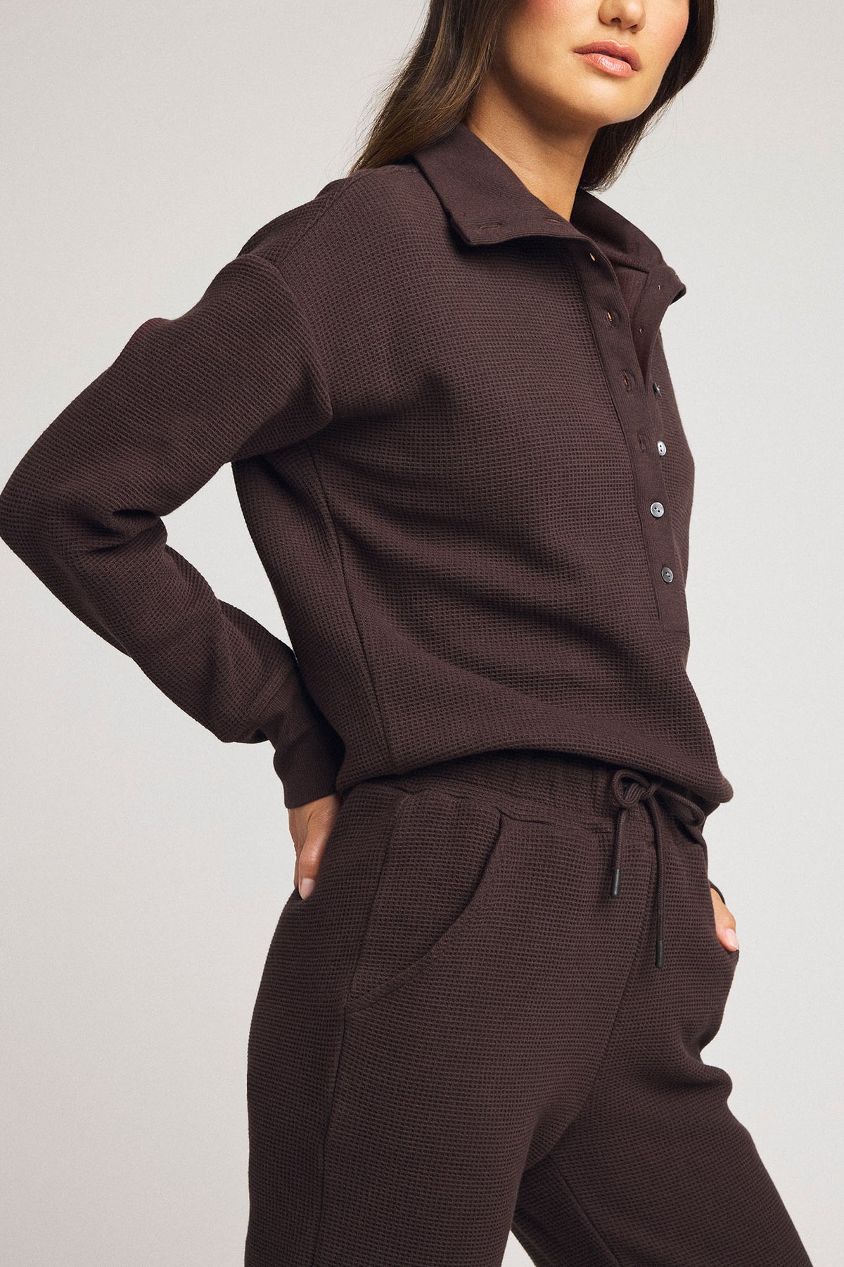 Dark brown waffle-knit henley pullover with long sleeves, collar, and button placket