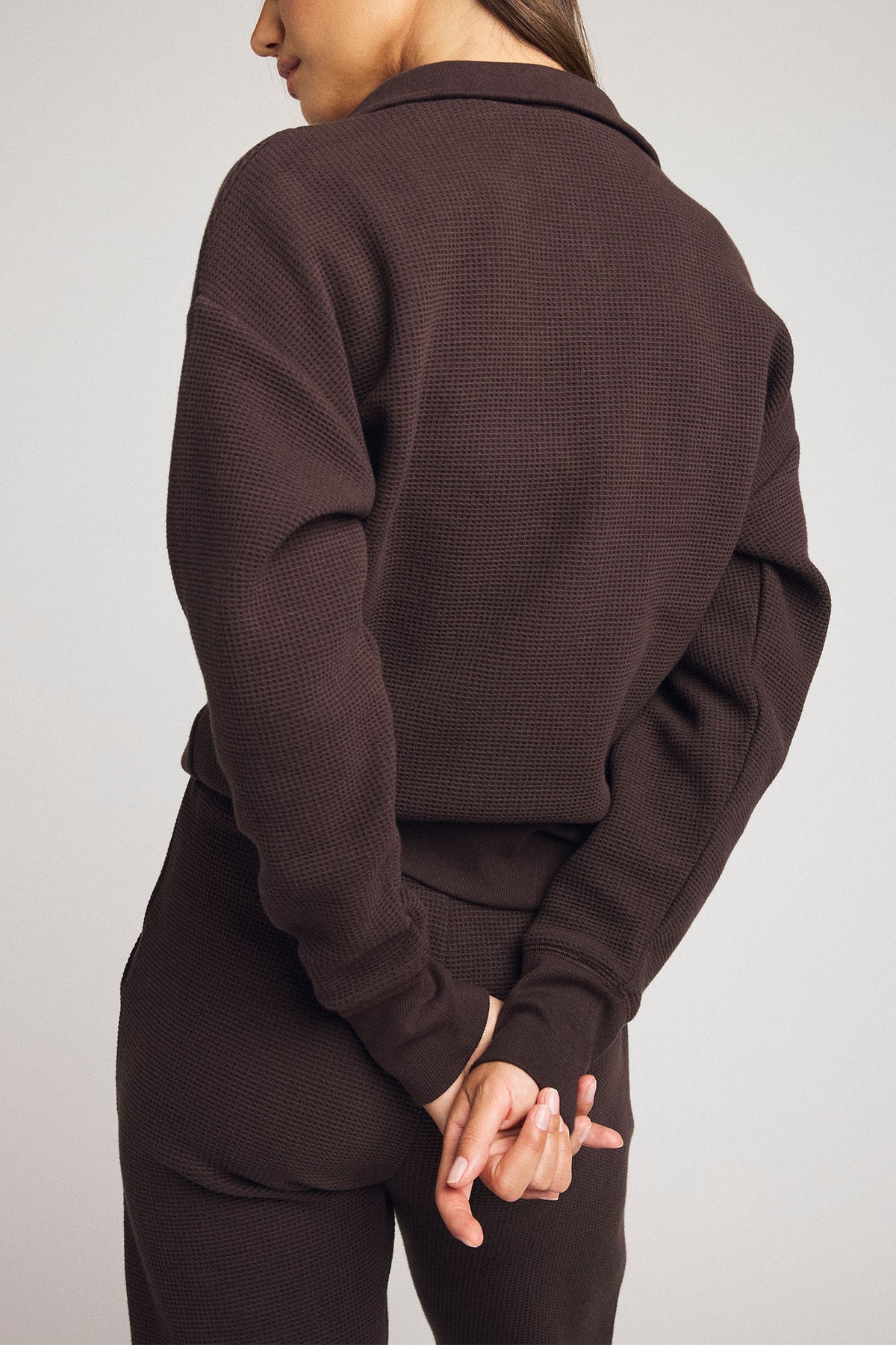 Dark brown waffle-knit pullover with long sleeves, back panel, and waist drawstring