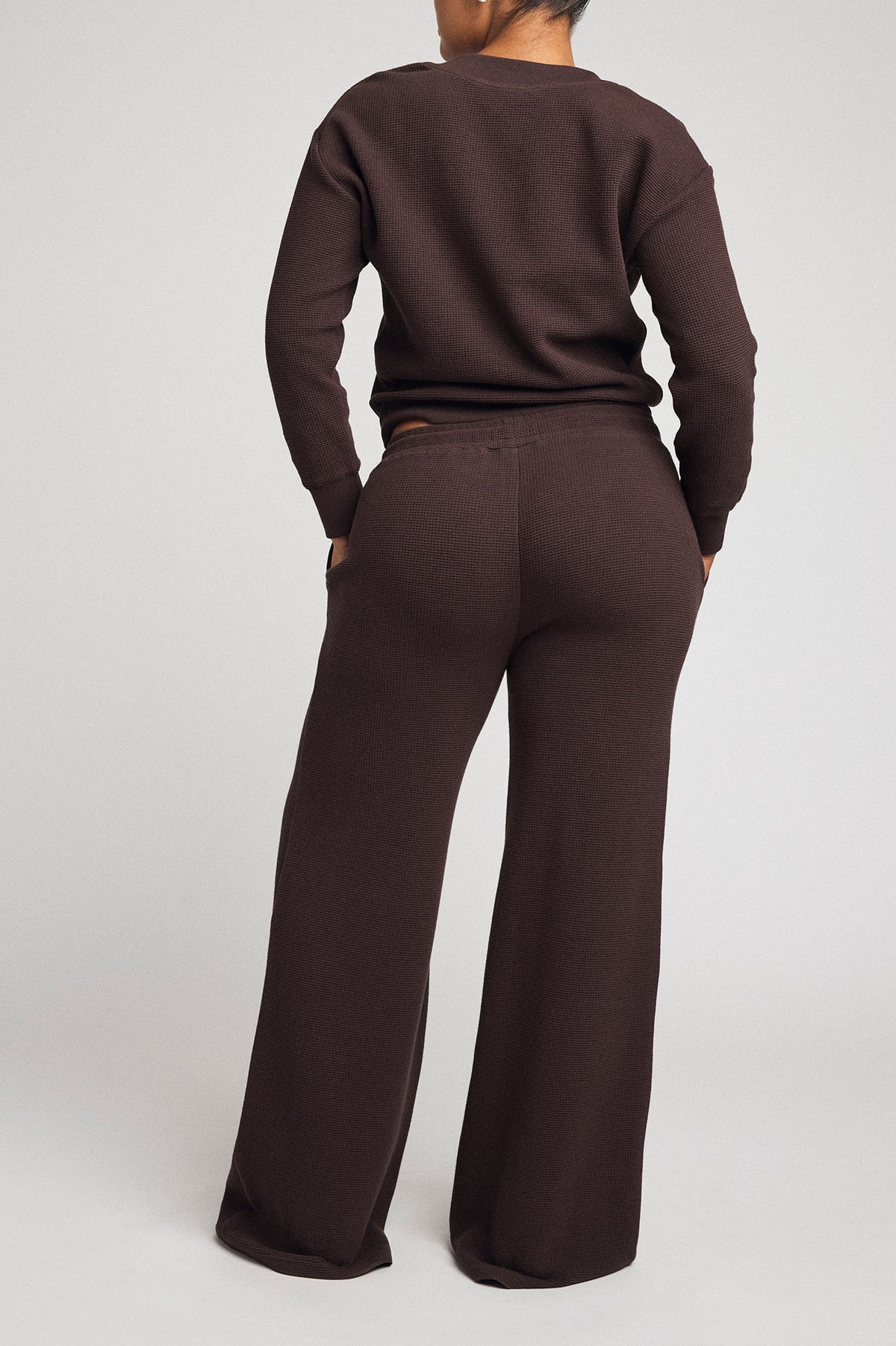 Back view of waffle knit track pants in dark brown with relaxed waistband and straight fit