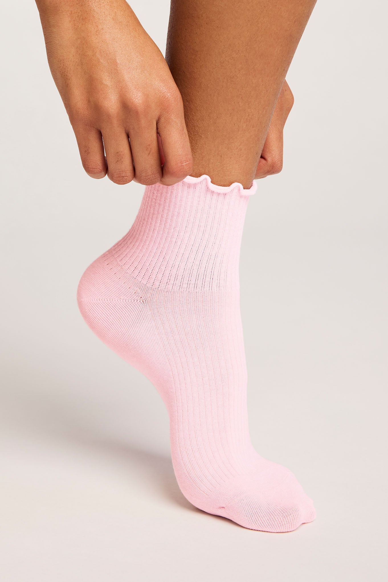 Person wearing a pink sock on a light background